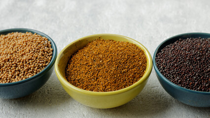 Powder spice blend from black and white mustard seeds and turmeric. Indian mustard powder seasoning in bowl.