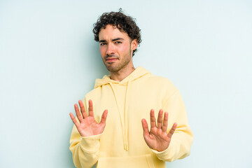 Young caucasian man isolated on blue background rejecting someone showing a gesture of disgust.