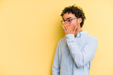 Young caucasian man isolated on yellow background being shocked because of something she has seen.
