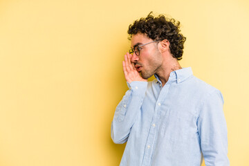 Young caucasian man isolated on yellow background is saying a secret hot braking news and looking aside