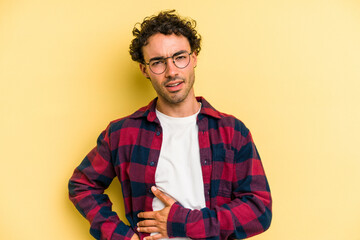 Young caucasian man isolated on yellow background having a liver pain, stomach ache.