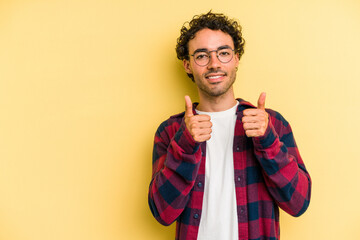 Young caucasian man isolated on yellow background smiling and raising thumb up