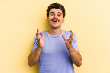 Young caucasian man isolated on yellow background laughs out loudly keeping hand on chest.