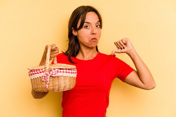 Young hispanic woman going to do it picnic isolated on yellow background feels proud and self confident, example to follow.