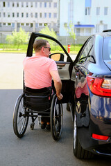 Fototapeta premium a person in a wheelchair learns to get into a car without assistance, driver with disability