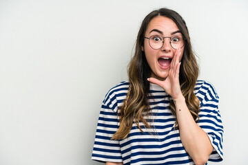 Young caucasian woman isolated on white background shouts loud, keeps eyes opened and hands tense.