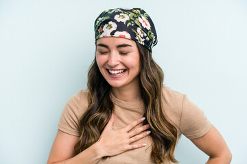 Young caucasian woman isolated on blue background laughing keeping hands on heart, concept of happiness.