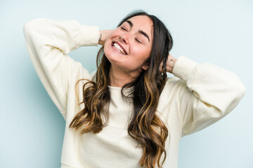 Young caucasian woman isolated on blue background feeling confident, with hands behind the head.