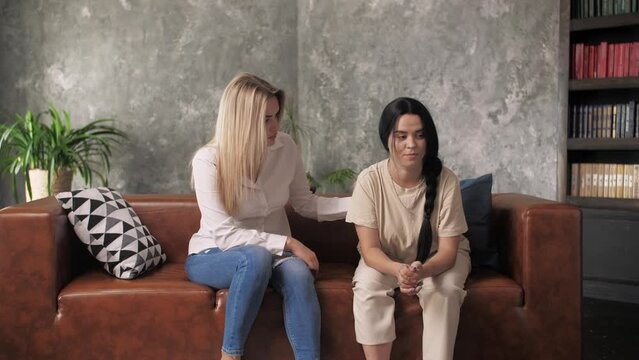 A young girl sitting on the couch tells a sad story to her friend