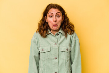 Young caucasian woman isolated on yellow background shrugs shoulders and open eyes confused.