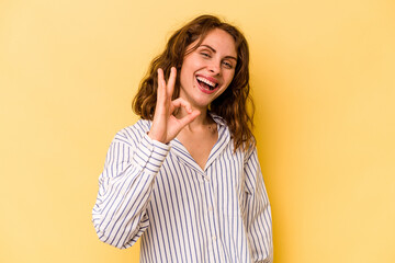 Young caucasian woman isolated on yellow background cheerful and confident showing ok gesture.