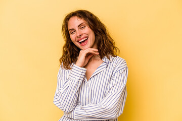Young caucasian woman isolated on yellow background smiling happy and confident, touching chin with hand.