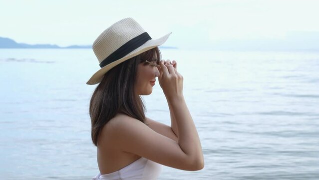 SLOW MOTION: Smiling Young asian wonan wearing hat and sunglasses sexy bikini on a seaside beach tropical resting and relaxation travel lifestyle, Happy female freedom on summer vacation time.