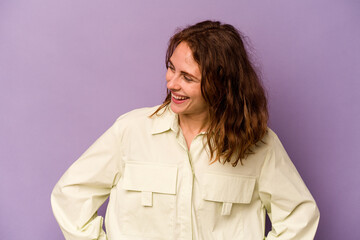 Young caucasian woman isolated on purple background laughs happily and has fun keeping hands on...