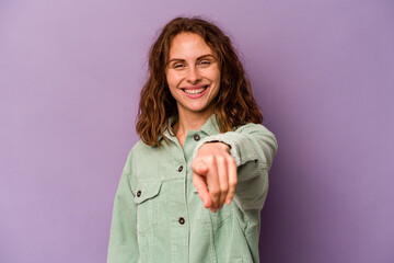 Young caucasian woman isolated on purple background cheerful smiles pointing to front.