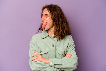 Young caucasian woman isolated on purple background funny and friendly sticking out tongue.