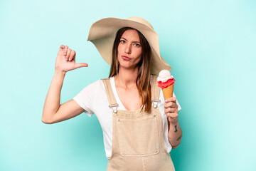 Young caucasian pregnant woman holding an ice cream isolated on blue background feels proud and self confident, example to follow.