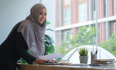 Fototapeta na wymiar Successful young muslim female corporate CEO planning investment strategy for startup project, working with financial document at office.