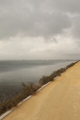 path of dirt road next the water ocean with reflection of sunlight