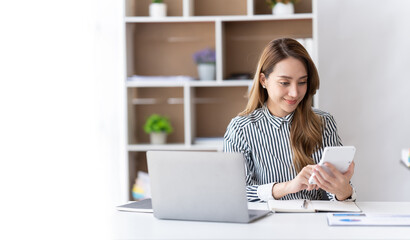 Portrait of asian business woman paying bills online with laptop in office. Beautiful girl with...