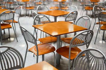 Wooden tables and chairs at large empty foodcourt in mall