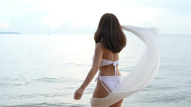 SLOW MOTION: Smiling Young asian woman bikini sexy with shawl on a seaside beach tropical resting and relaxation travel lifestyle, Happy female freedom on summer vacation time on weekend.