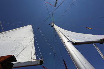 White Sailboat of the vessel floating on the sea with bright sun and blue sky