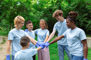 Fototapeta premium Portrait of volunteers folding their arms. Environmentalists are in a public park. They are in blue T-shirts. The concept of friendship and helping