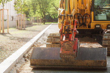 Excavator Constructs New Sidewalk Footpath in park. Excavator works with wide bucket. Road works.  © Maryana