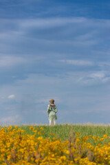 Obraz premium 夏の公園の芝生にいる綺麗な若い女性と青空と黄色い満開の花の風景