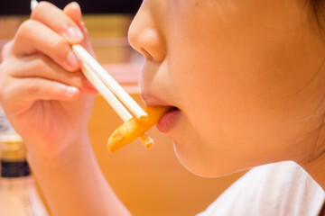 店で箸を使ってポテトを食べる子供の口の写真