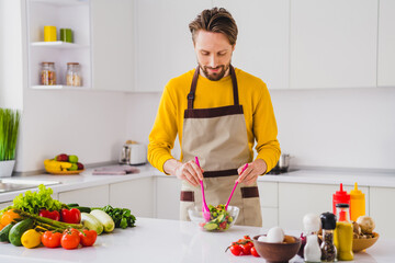 Photo of young cheerful guy cook fresh salad mix vegan ecological prepapre kitchen dinner dish indoors