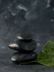 Stacked Massage stones with leaves on a dark stone table