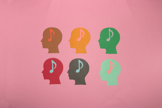 six colorful paper head with musical notes in the head on a pastel pink background, day of music, day of listening, happiness enjoyment on vacation and musical
