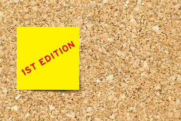 Yellow note paper with word 1st edition on cork board background with copy space