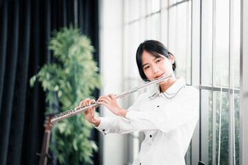 Young woman flutist performs on a musical instrument