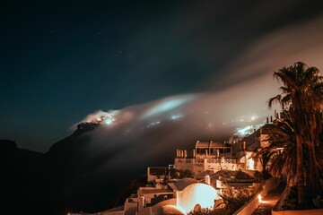 Misty cloud forming over the village of Imerovigli in Santorini, Greece on a beautiful starry night