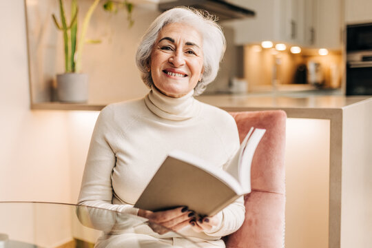 Mature woman smiling happily while reading a book