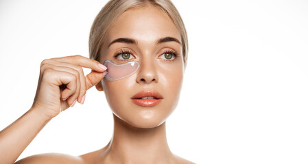 Close up, woman with perfect glowing facial skin, puts on under eye cosmetic patches from dark...
