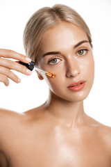 Fototapeta premium Beauty and skin care concept. Face of woman applying tea tree and lemon facial C-Serum, using anti-aging treatment products, hydrating and nourishing skin for better tone