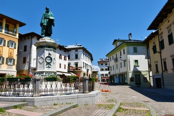 Pieve di Cadore, Italy - June 19 2022: Central Tiziano square in the town of Pieve di Cadore in Veneto region and Belluno province in Italy with an old statue
