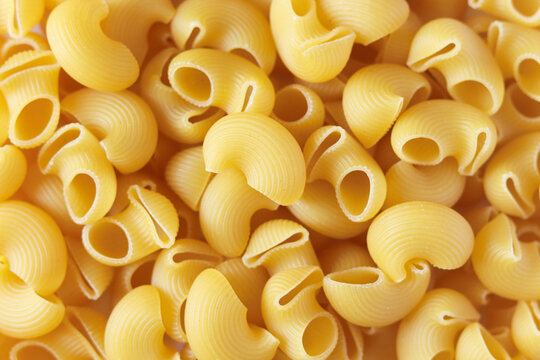 Uncooked pipe rigate pasta background. Italian raw pasta. Lumaconi type.