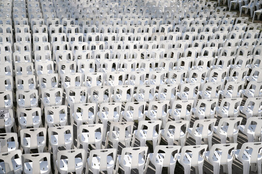 Many white plastic chairs were set up in a square area with the row and column for outdoor concerts or open air events.