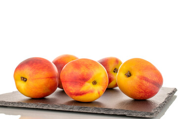 Several juicy organic nectarines on a slate stone, close-up, isolated on a white background.