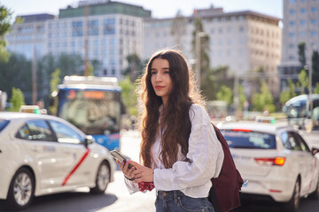 woman waiting for ride share as taxi cabs drive by in Spain - obrazy, fototapety, plakaty