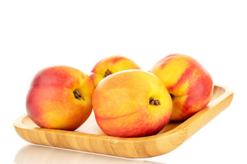 Several juicy organic nectarines on a wooden tray, close-up, isolated on a white background.