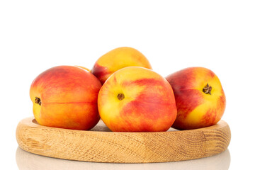Several juicy organic nectarines on a wooden tray, close-up, isolated on a white background.
