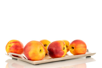 Several juicy organic nectarines on a metal tray, close-up, isolated on a white background.