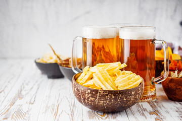 mug of beer and a set of dry fish snacks on a white wooden rustic background