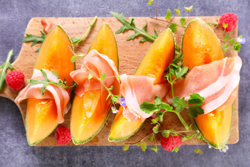 Cantaloupe melon slices with prosciutto ham and raspberries